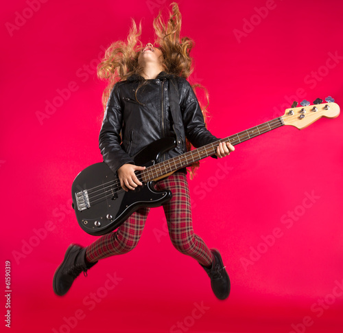 Blond Rock and roll girl with bass guitar jump on red photo