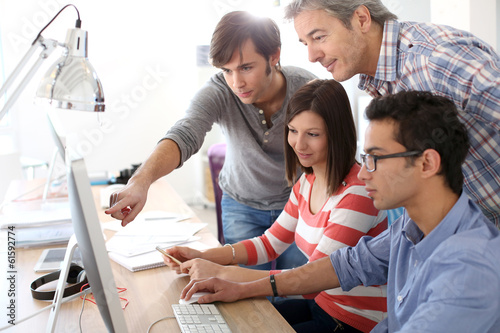 Teacher with students working on desktop photo