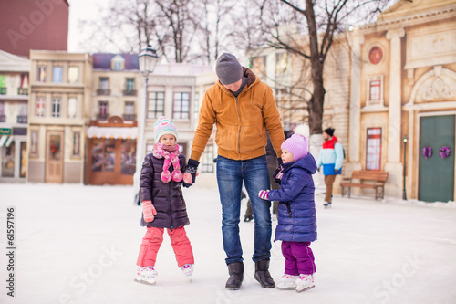 Little girls with young father enjoying skating