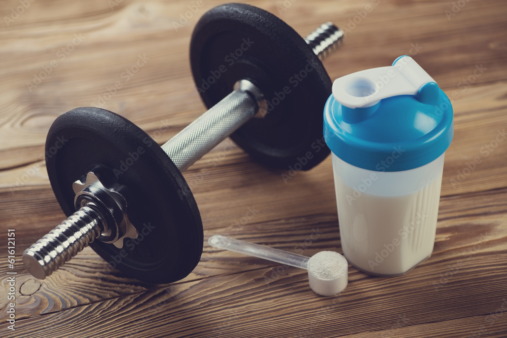 Bodybuilding components: protein shake with a dumbbell Bodybuilding components: protein shake with a dumbbell