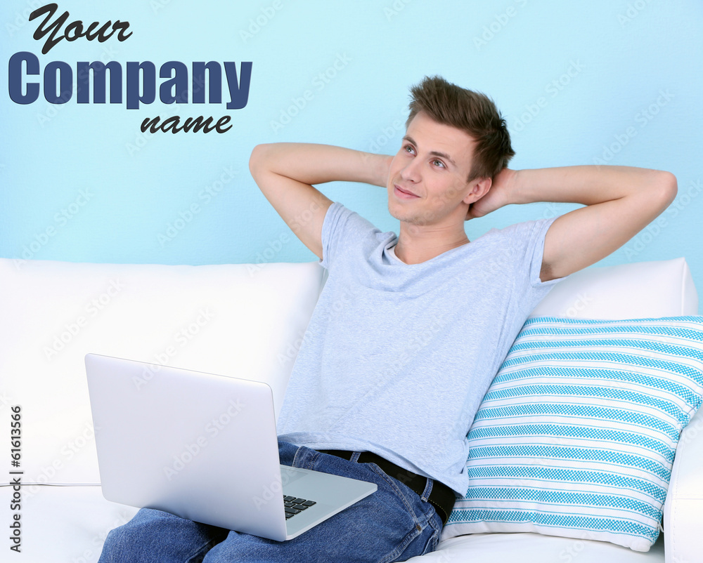 Guy sitting on sofa with laptop on blue background Guy sitting on sofa with laptop on blue background