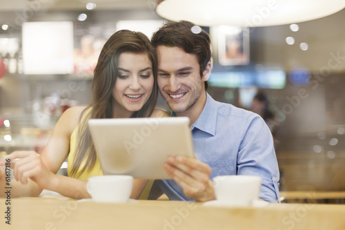 Couple have fun with digital tablet in cafe