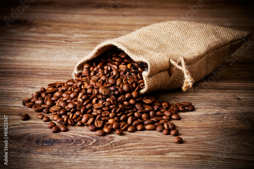 The sack of coffee beans on wooden background © Vitaly Raduntsev