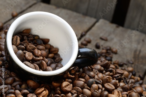 Schmackhafte Kaffeebohnen auf Holzuntergrund mit Tasse photo