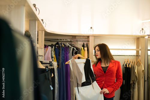 Woman shopping choosing dresses looking in mirror uncertain