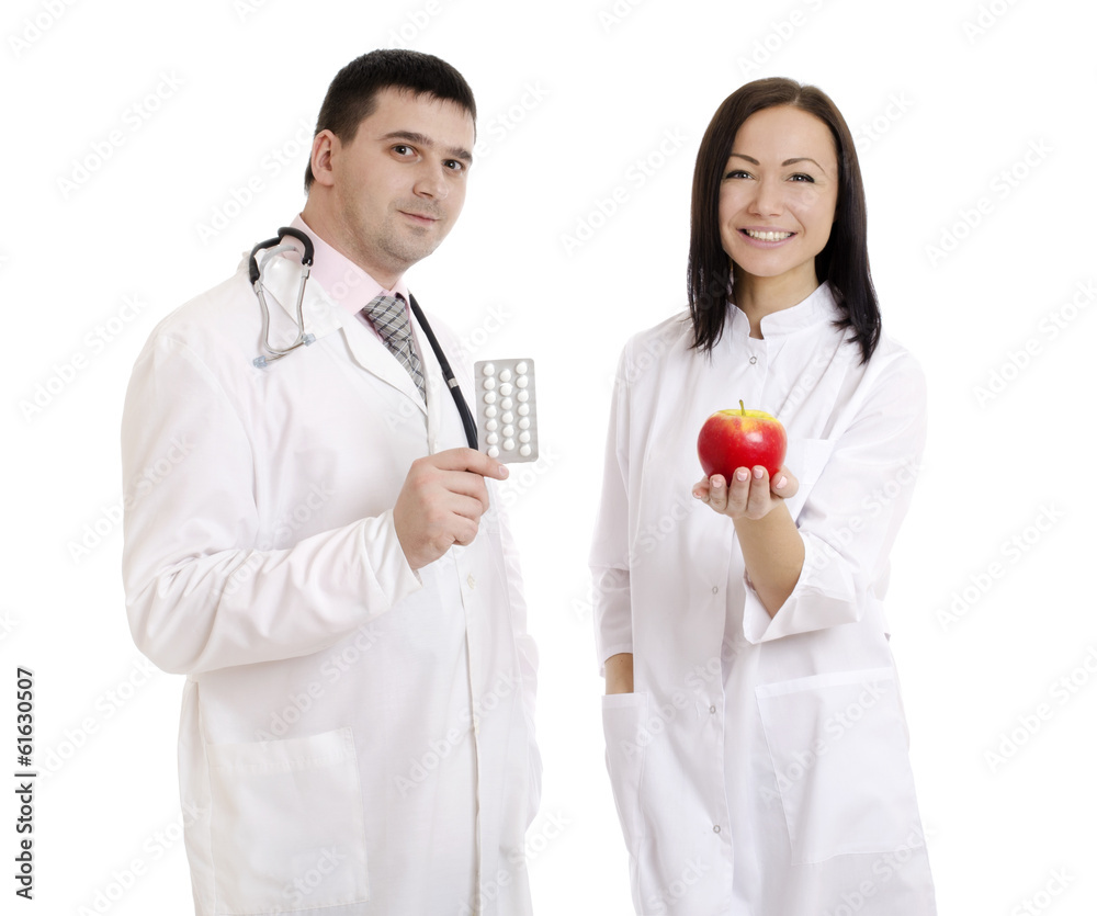 Male and female doctors holding apple and pills - Stock Image Male and female doctors holding apple and pills - Stock Image