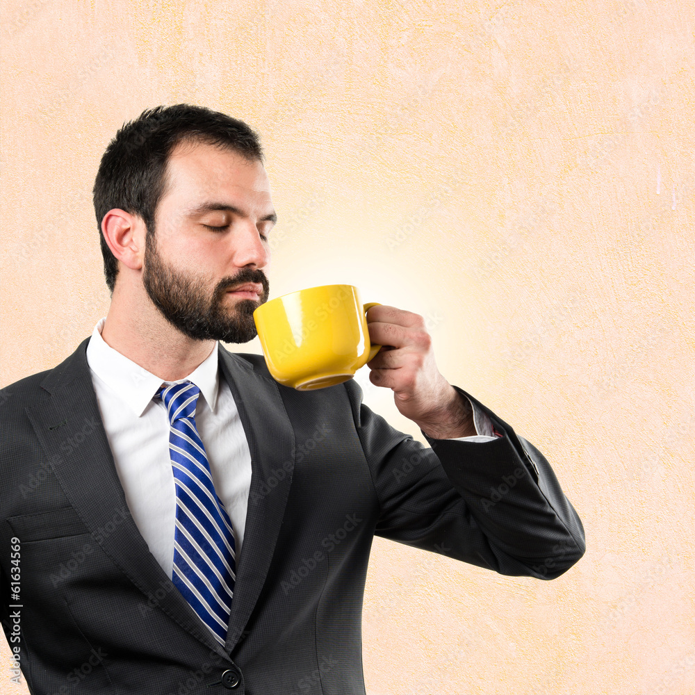Young businessman drinking a coffee over ocher background Young businessman drinking a coffee over ocher background
