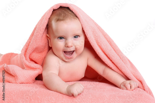 Smiling baby in pink towel. Cute baby lies on his tummy and looks forward. A sweet child.