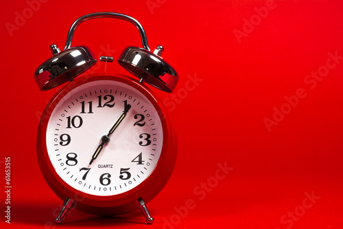 A red vintage alarm clock on a red background with copy space