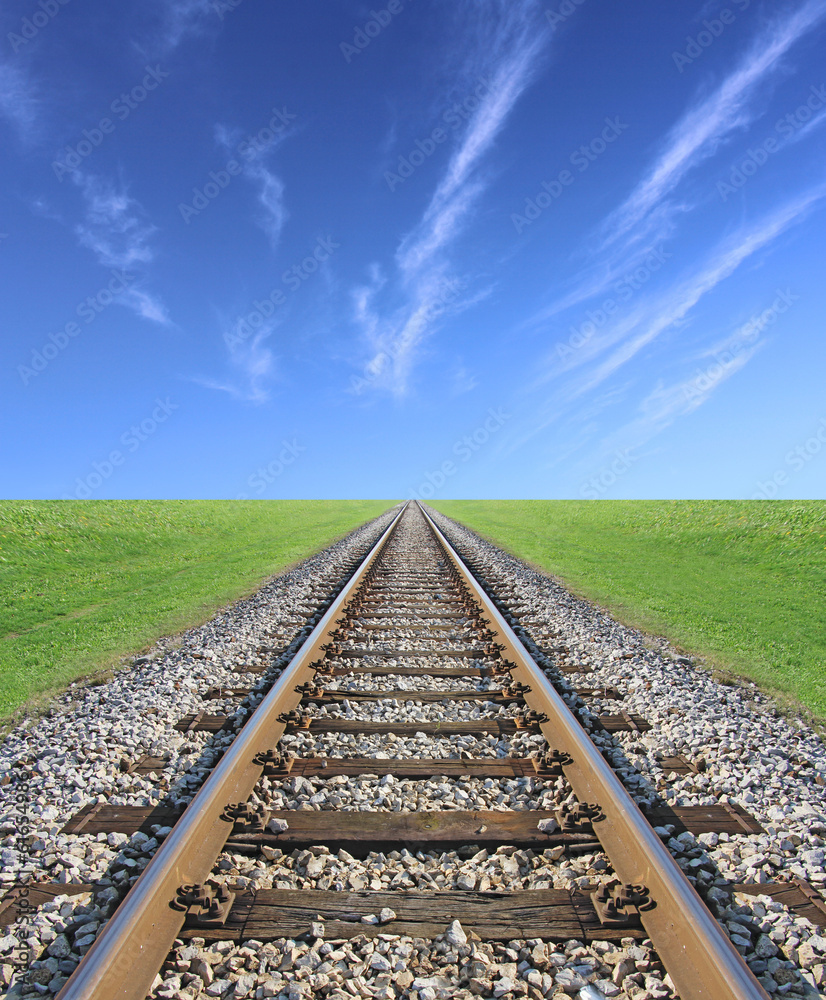 Railway track, green grass and blue sky on the horizon Railway track, green grass and blue sky on the horizon