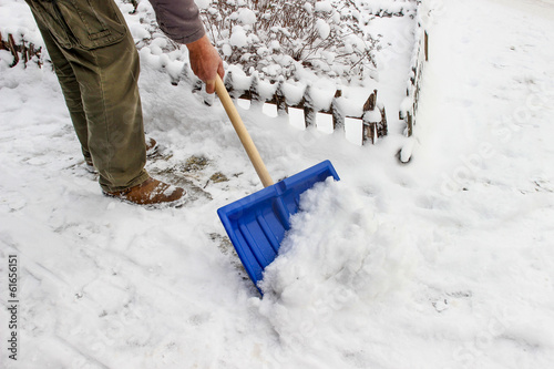 Man removing snow from the sidewalk after snowstorm