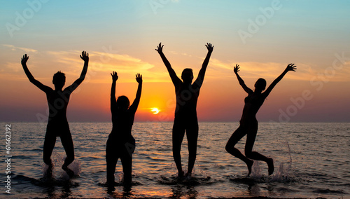 silhouette of jumping people on sunset background