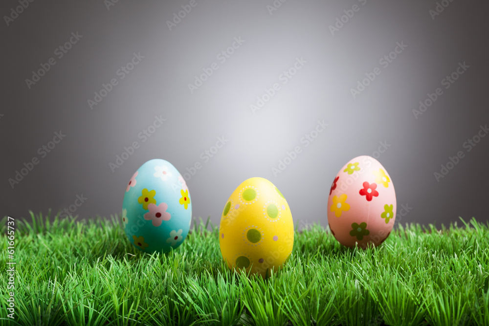 Colored easter eggs in grass, gray background