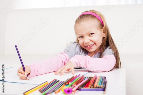 Cute little girl drawing with colored pencils at home.