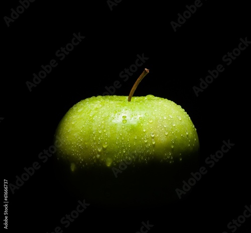 fresh green apple with droplets of water on black background