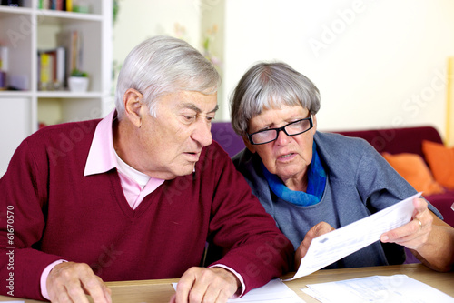Senior couple reading bills at home