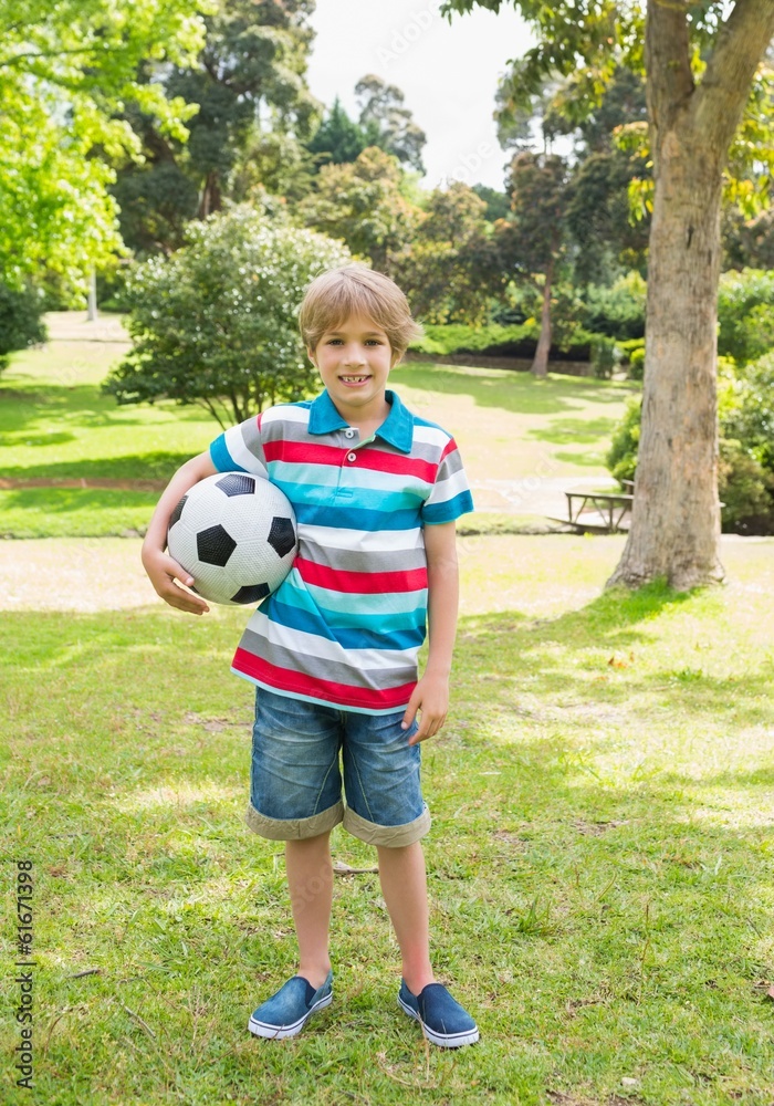 Full length portrait of a boy with ball at park