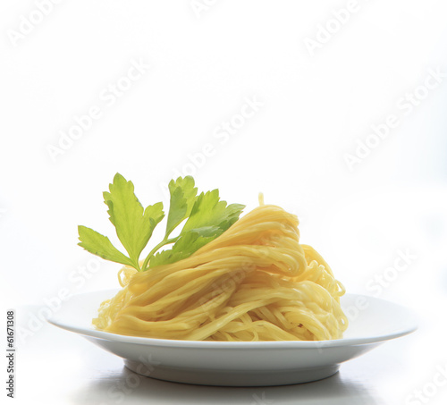 chinese yellow eggs noodle on white disk with green leaves of ce
