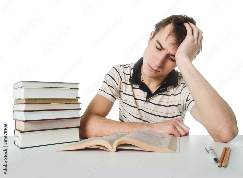 Male student at the table with pile of books Male student at the table with pile of books