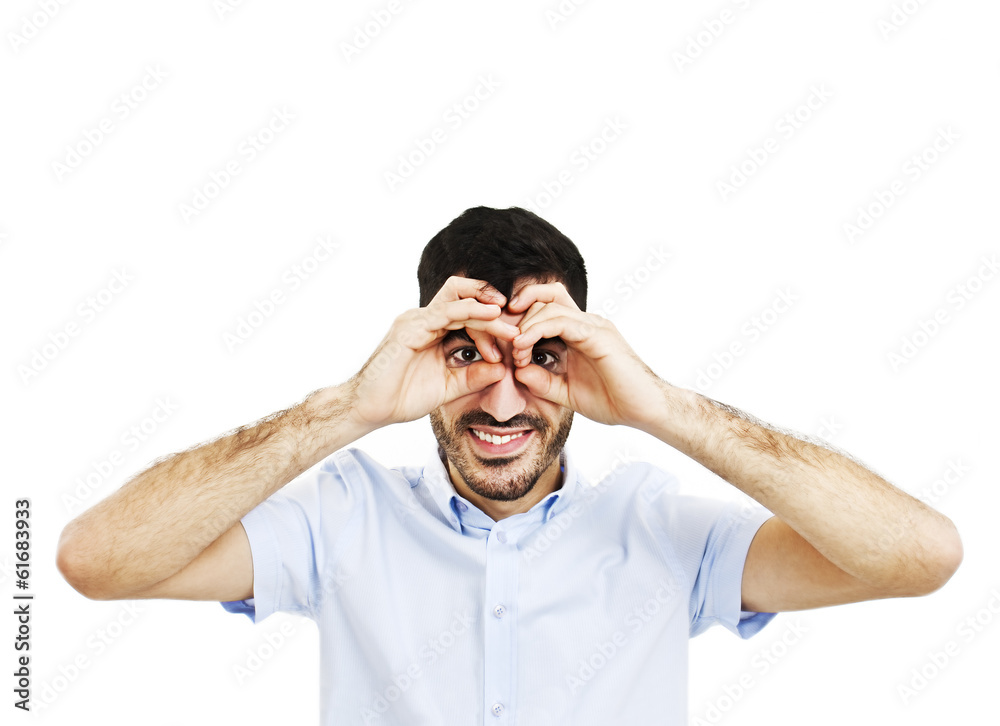 Naklejka premium Handsome young man smiling, making binoculars with his hands