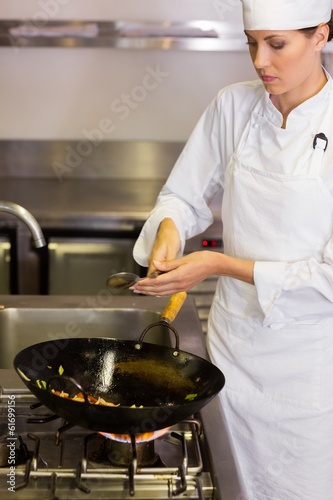 Concentrated female chef preparing food in kitchen