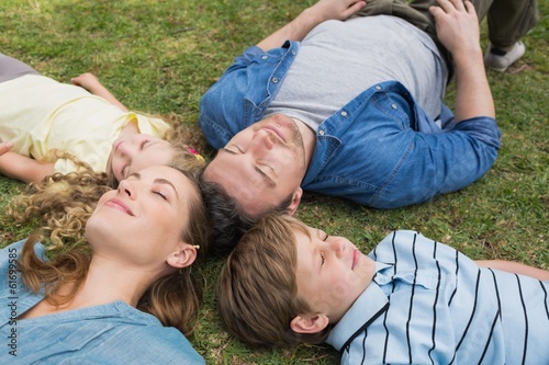 Family lying on grass with eyes closed at park