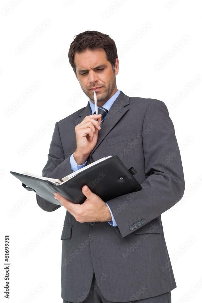 Handsome thoughtful businessman holding his diary Handsome thoughtful businessman holding his diary