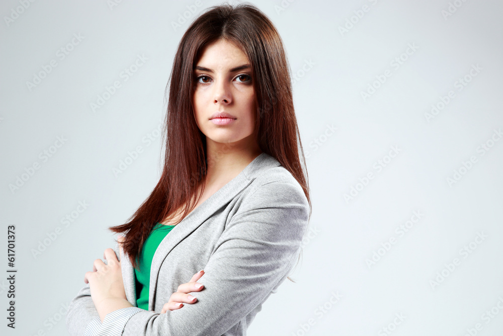 Beautiful woman standing with arms folded on gray background Beautiful woman standing with arms folded on gray background