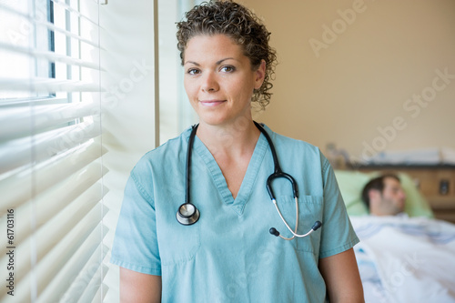Confident Nurse With Patient In Background