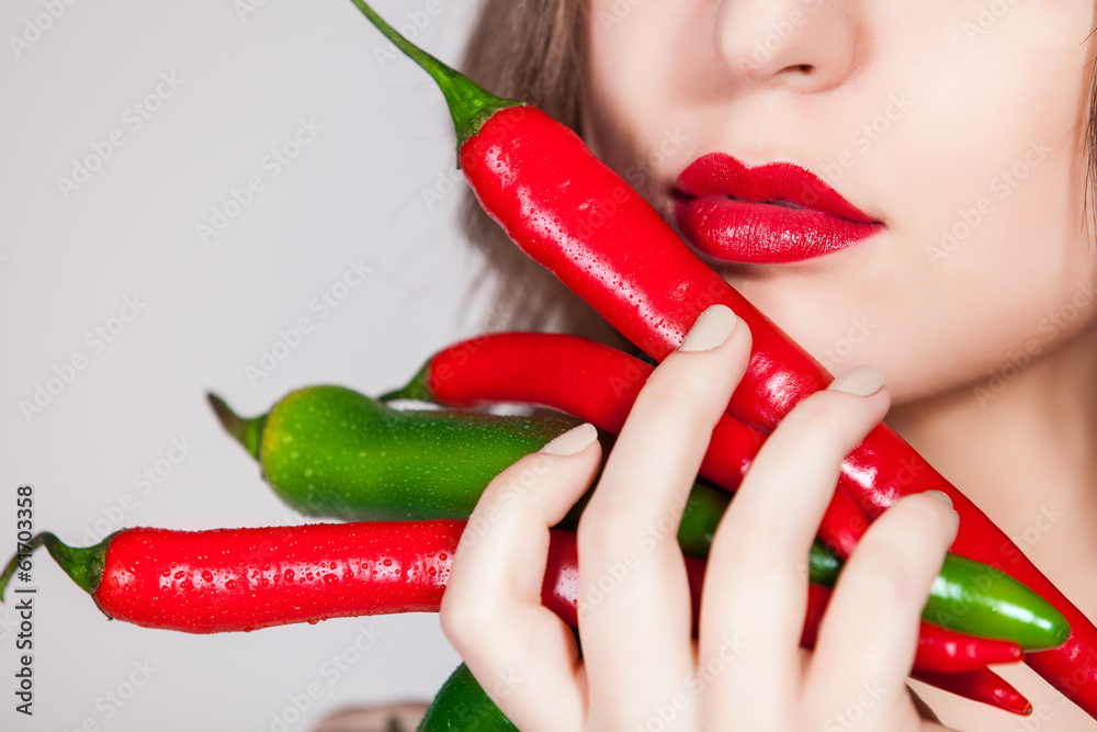 Cropped studio shot of a attractive woman holding up peppers Cropped studio shot of a attractive woman holding up peppers