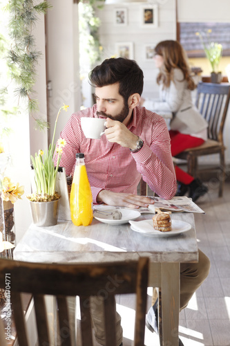 Modern young man sitting in coffee shop