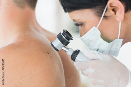 Dermatologist examining mole on patient photo
