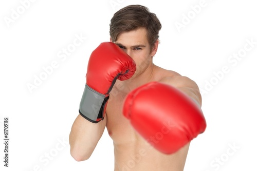 Tough man wearing red boxing gloves punching to camera