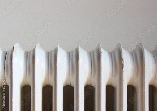 Closeup on worn radiator with white wall background