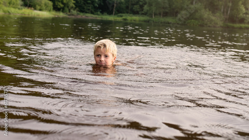 Fototapeta Naklejka Na Ścianę i Meble -  Boy swimming in a lake late afternoon