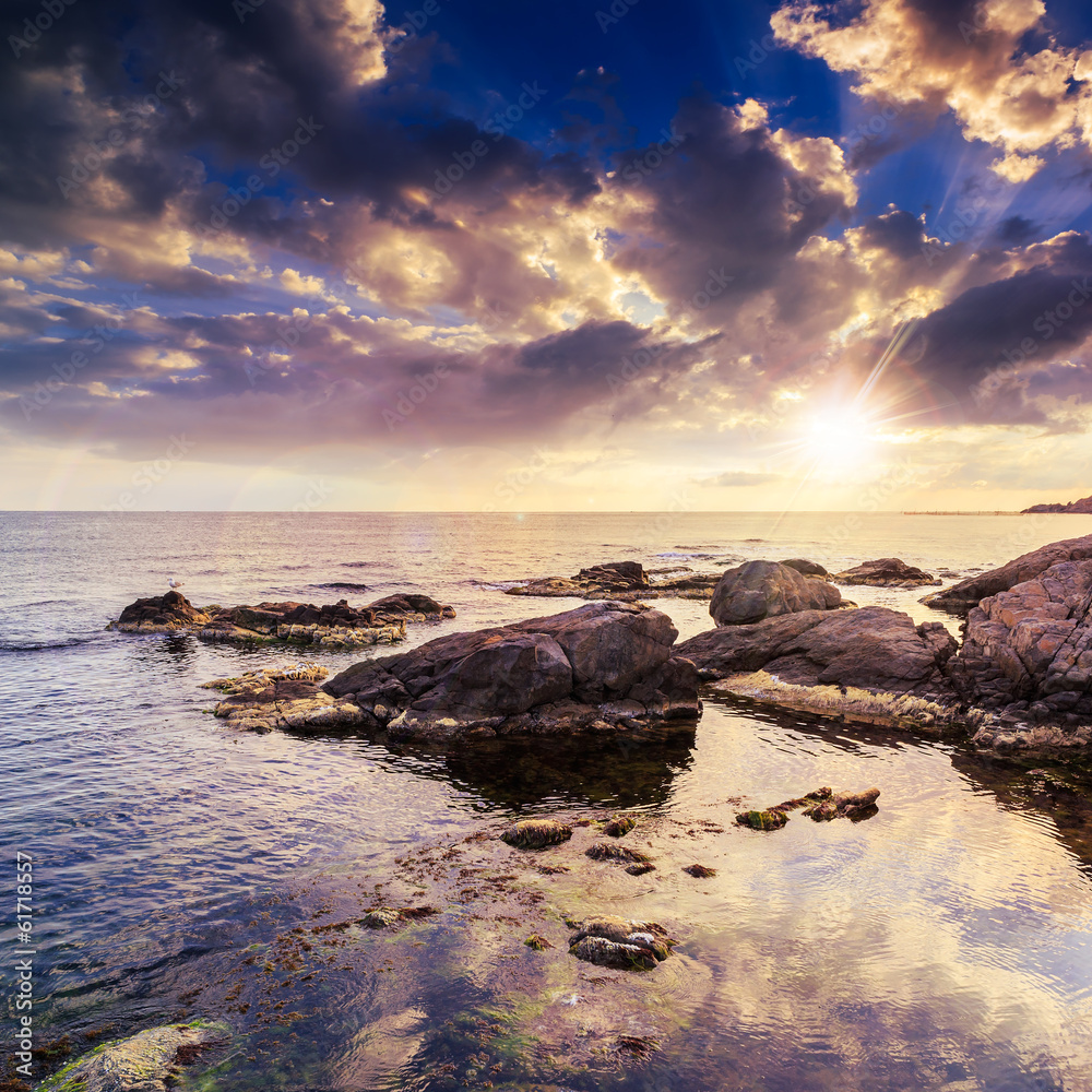 Obraz premium sea wave breaks about boulders at sunset