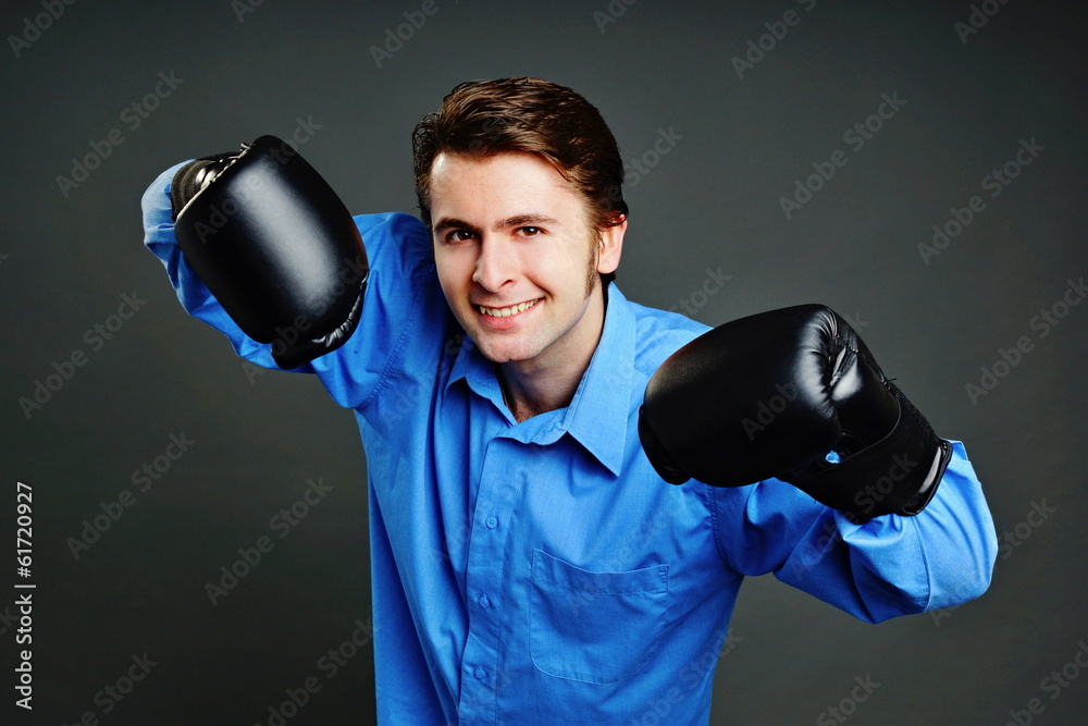 Young man at blue shirt with boxing gloves on his hands Young man at blue shirt with boxing gloves on his hands