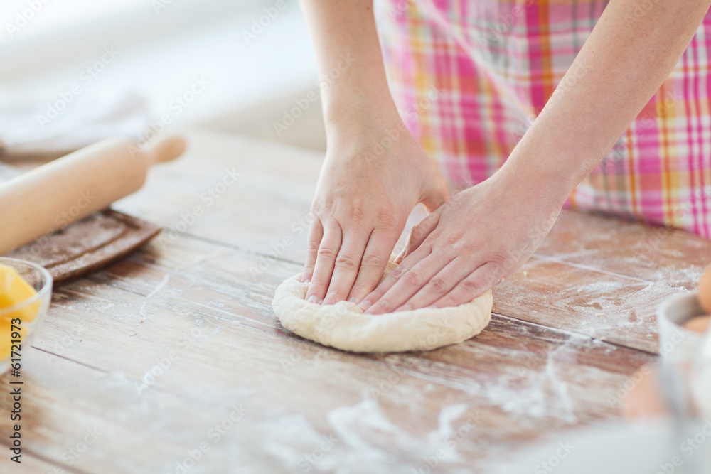 close up of female hands kneading dough at home