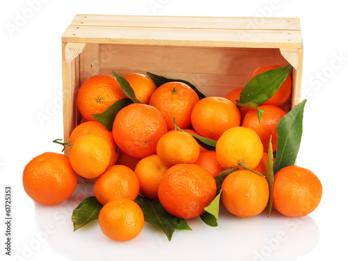 Ripe tasty tangerines with leaves in wooden box dropped