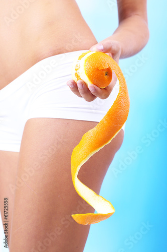 Beautiful young woman with orange on blue background