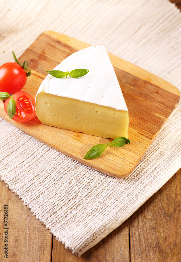 Tasty Camembert cheese with tomato and basil, on wooden table Tasty Camembert cheese with tomato and basil, on wooden table