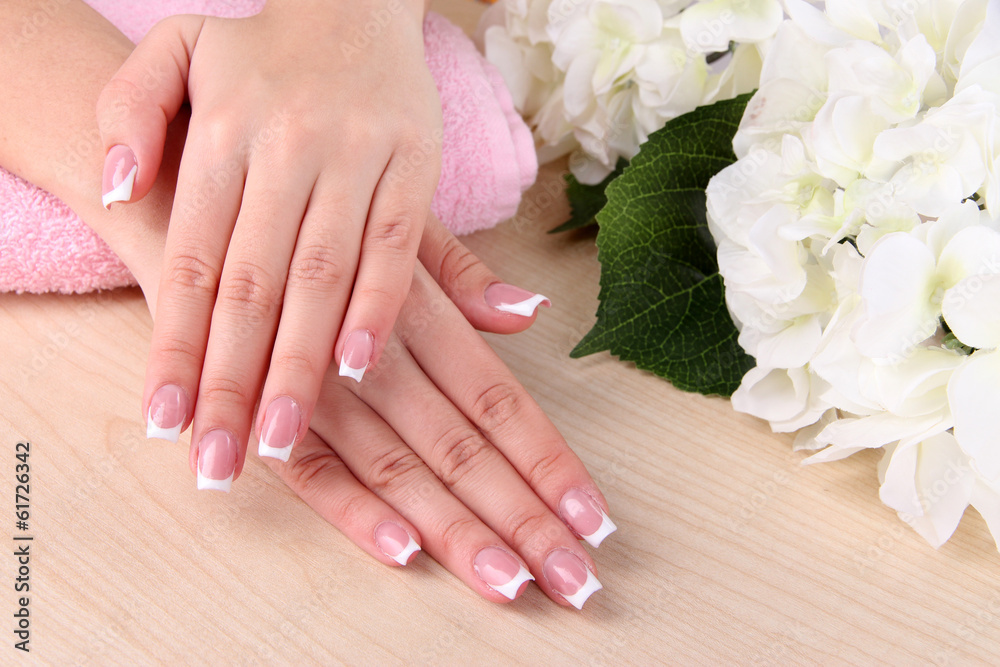 Fototapeta premium Beautiful woman hands with french manicure and flowers