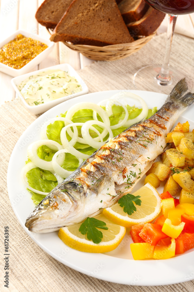 Delicious grilled fish on plate on table close-up