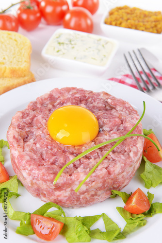 Delicious steak tartare with yolk on plate on table close-up