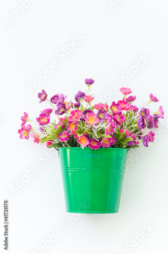Plastic flower in vase on wall background