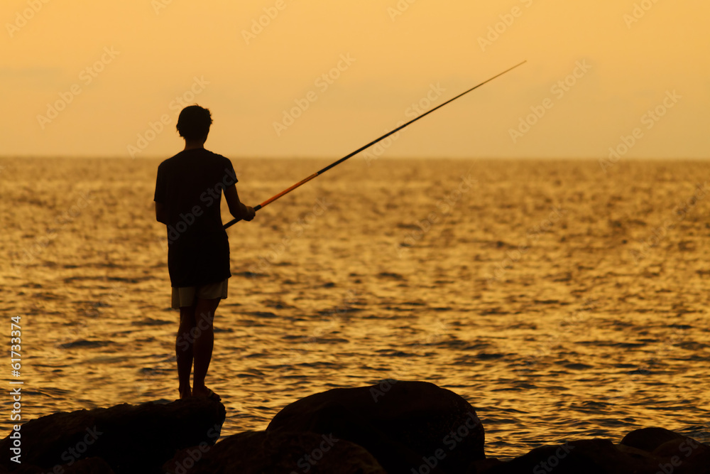 Silhouette of a fisherman at sunset