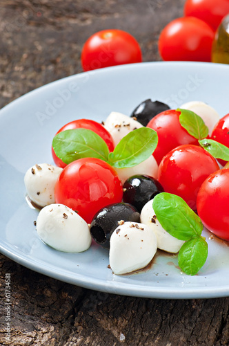 Fresh salad with cherry tomatoes, basil, mozzarella and olives