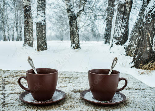 Two cups of tea on background of a winter landscape