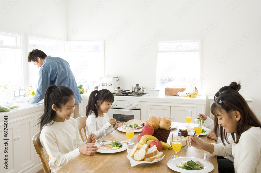 Japanese children gathering at table while father washing dishes