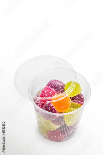 Colorful fruit jelly in open foam jar, on white background